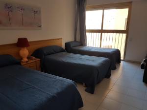 a room with two beds and a window with a window at Hotel Neptuno in Oropesa del Mar