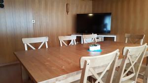 une grande table en bois avec des chaises et une télévision à écran plat. dans l'établissement Hotel Alpenblick Muotathal, à Muotathal