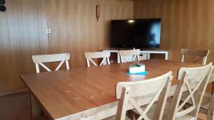 einen großen Holztisch mit Stühlen und einen Flachbild-TV in der Unterkunft Hotel Alpenblick Muotathal in Muotathal
