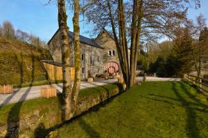 a large stone house with a red door and a yard at River Lodge Hotel Insolite in Maredsous