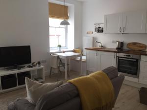 a living room with a couch and a kitchen at Little Arch in Tenby