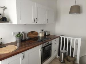 a kitchen with white cabinets and a wooden counter top at Little Arch in Tenby