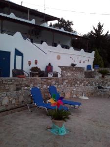 two blue chairs and a plant in a courtyard at Studios Avra in Akhladherí