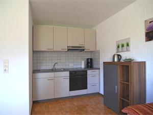 eine Küche mit weißen Schränken, einer Spüle und einem Herd in der Unterkunft Modern Apartment in Sellinghausen with Terrace in Schmallenberg