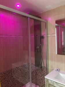 ein Bad mit einer Dusche und einem Waschbecken mit rosa Lichtern in der Unterkunft Apartamentos Las Ferrerias in Arenas de San Pedro