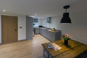 a kitchen with a wooden table in a room at Honeysuckle Cottage, Drift House Holiday Cottages in Astbury