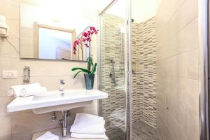 
a bathroom with a sink, mirror, and toilet at Alma di Alghero Hotel in Alghero
