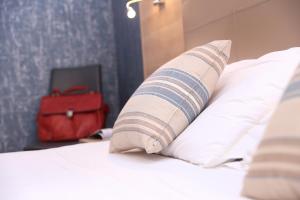 a bed with a pillow and a red suitcase at Alma di Alghero Hotel in Alghero