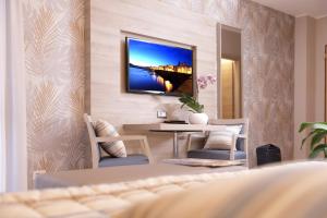 a living room with a table and a tv on the wall at Alma di Alghero Hotel in Alghero