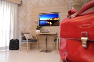 a room with a room with a tv and a suitcase at Alma di Alghero Hotel in Alghero