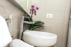 a bathroom with a white sink and a purple flower at Alma di Alghero Hotel in Alghero
