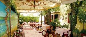 Un restaurante con mesas y sillas y una sombrilla. en Albergo Ristorante Alle Castrette, en Villorba