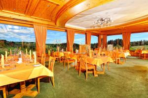 a dining room with tables and chairs and large windows at Landhotel Talblick in Neuweiler