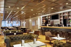 un restaurante con sofás y mesas y un bar en H4 Hotel Leipzig, en Leipzig