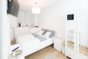 a white bedroom with a bed and a tv at Miniapartment am Dalberg in Aschaffenburg
