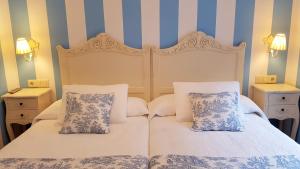 two beds in a bedroom with blue and white stripes at Legado de Ugarte, Casa Rural in Laguardia