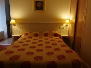 a bedroom with a bed with a floral bedspread on it at Le relais de l'Argoat in Belle-Isle-en-Terre