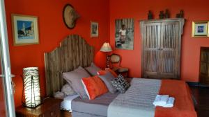 een slaapkamer met een bed met een oranje muur bij Gîte L'Appart de Case Vanille in Sari Solenzara