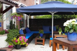 a patio with a blue couch and an umbrella at Hotel Albion in Scheveningen