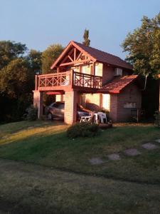 a house with a balcony and a car in the yard at Cabañas Dalga Inn in Merlo