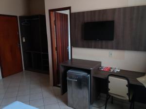 Habitación con escritorio y TV en la pared. en Hotel Central en Porto Velho