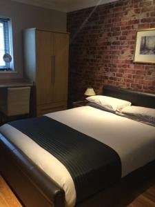 a bedroom with a bed and a brick wall at Lakeland Guest House in Pembroke Dock