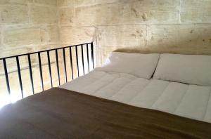a white bed in a room with a brick wall at Xemx in Qala
