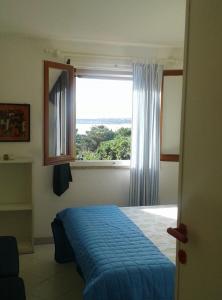 a bedroom with a blue bed and a window at Giulianahouse in La Maddalena