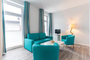 uma sala de estar com duas cadeiras, um sofá e uma mesa em Ria‘s Beachhouse em Borkum