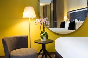 a hotel room with a mirror and a chair and a bed at Boutique Hotel Des XV in Strasbourg