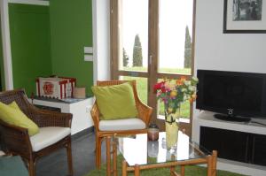 a living room with chairs and a table and a tv at Agriturismo Casa del Castagneto in Gargnano
