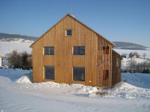 una casa de madera en la nieve con nieve alrededor en Apartmán u Kamila, en Dolní Morava