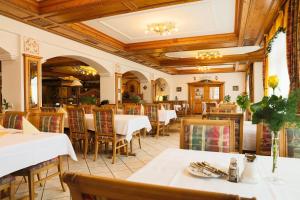 Sattelbogener Hof في Traitsching: مطعم بطاولات بيضاء وسقف خشبي