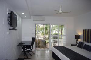 a bedroom with a bed and a desk and a television at Colonial Palms Motor Inn in Airlie Beach