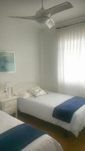 1 dormitorio blanco con 2 camas y ventana en La Casa de los Peces, en Peñíscola