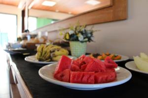 une table comportant des plaques de pastèque et d’autres fruits dans l'établissement Pousada Solar dos Guaras, à Catas Altas