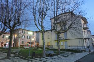 un edificio con árboles y bancos delante de él en Maison Bury, en Rapolano Terme