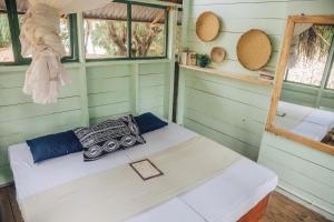 Cama en habitación con paredes y ventanas verdes en Mikadi Beach Camp & Backpackers, en Dar es Salaam