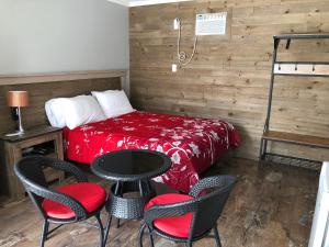 a room with a bed, table, chairs and a lamp at Motel La Source in Coaticook