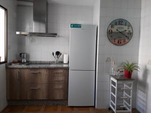 een witte koelkast in een keuken met een klok aan de muur bij ANDALUCIA 57 in Estepona