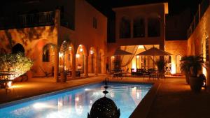 塔鲁丹特Riad Jardin des Orangers的夜晚建筑物前的游泳池