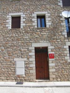un edificio de piedra con puerta de madera y 3 ventanas en Benages-Chiva, en Puertomingalvo
