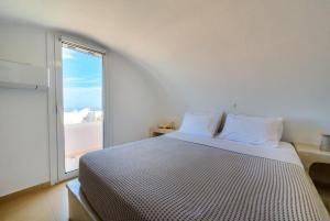 a white bedroom with a large bed with a window at Santorini’s Diamond Houses in Karterados +52 photos