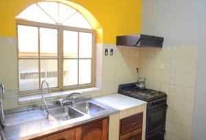 a kitchen with a sink and a stove and a window at Hostal Alamo in Cafayate +6 photos