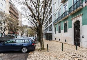 ein blaues Auto, das neben einem Baum neben einem Gebäude parkt in der Unterkunft FLH Avenida da Liberdade Amazing Flat in Lissabon