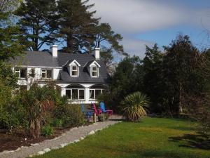 une maison blanche avec une terrasse couverte et une cour dans l'établissement Ballycommane House & Garden, à Durrus