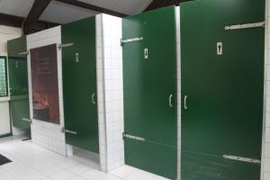 a row of green doors in a bathroom with tiles at Pipowagen in Tynaarlo