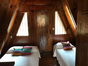 twee bedden in een kamer met twee ramen bij Cabaña EL CAPRICHO in Pátzcuaro