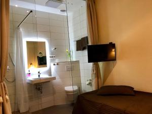 een badkamer met een wastafel, een toilet en een spiegel bij Pension Karina Schwerin in Schwerin