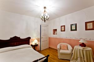 a bedroom with a bed and a chair and a chandelier at Villa Osperellone in Perugia